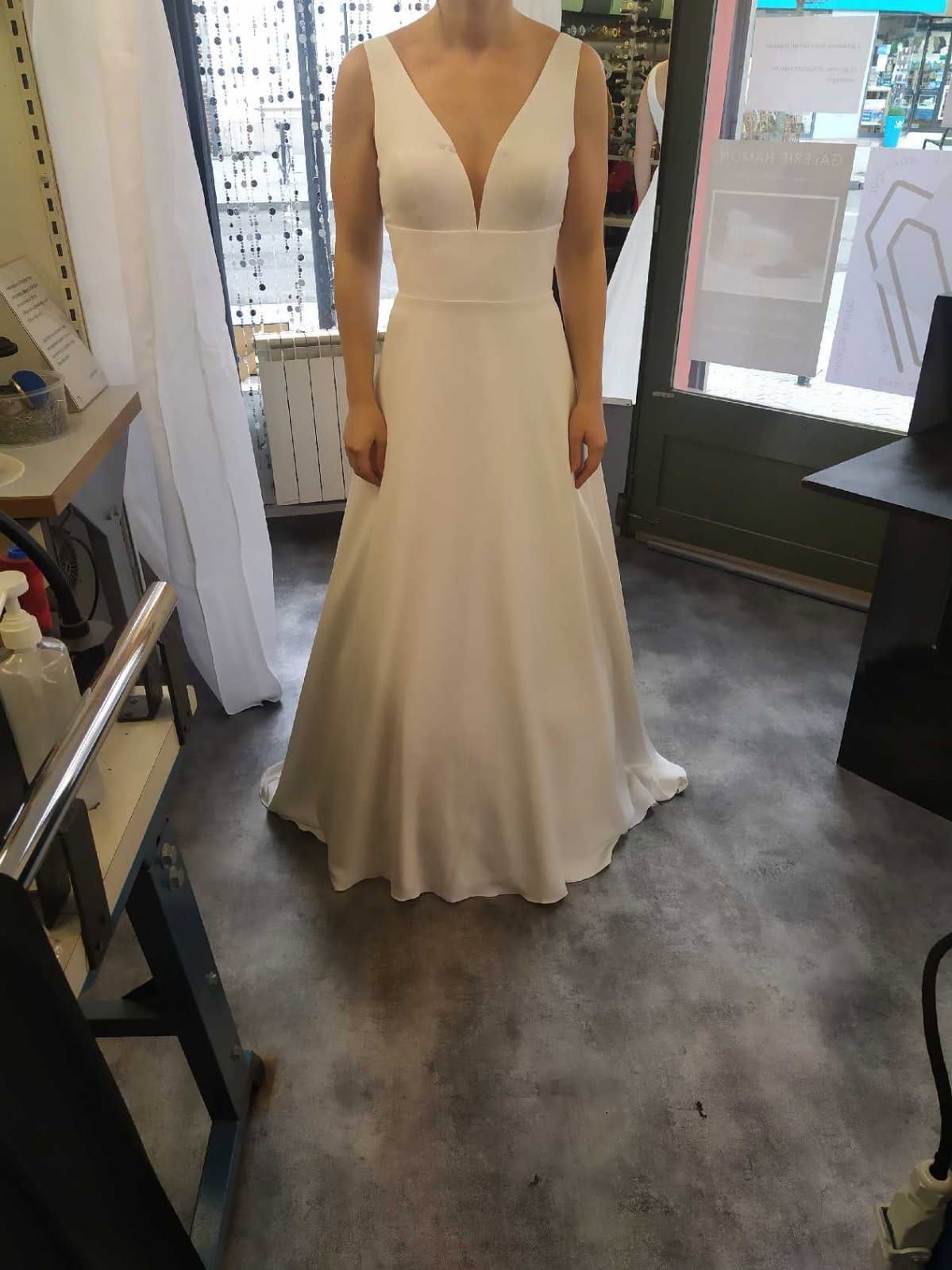 Une femme en robe de mariée blanche se tient dans une pièce.