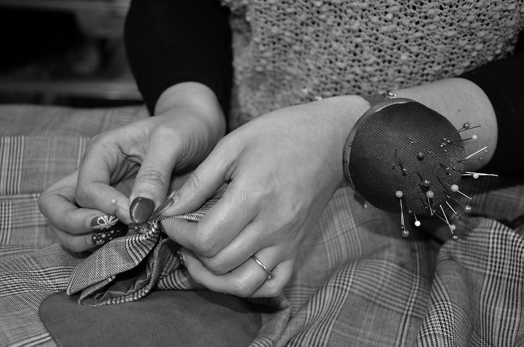 Une photo en noir et blanc des mains d'une femme travaillant sur un morceau de tissu.