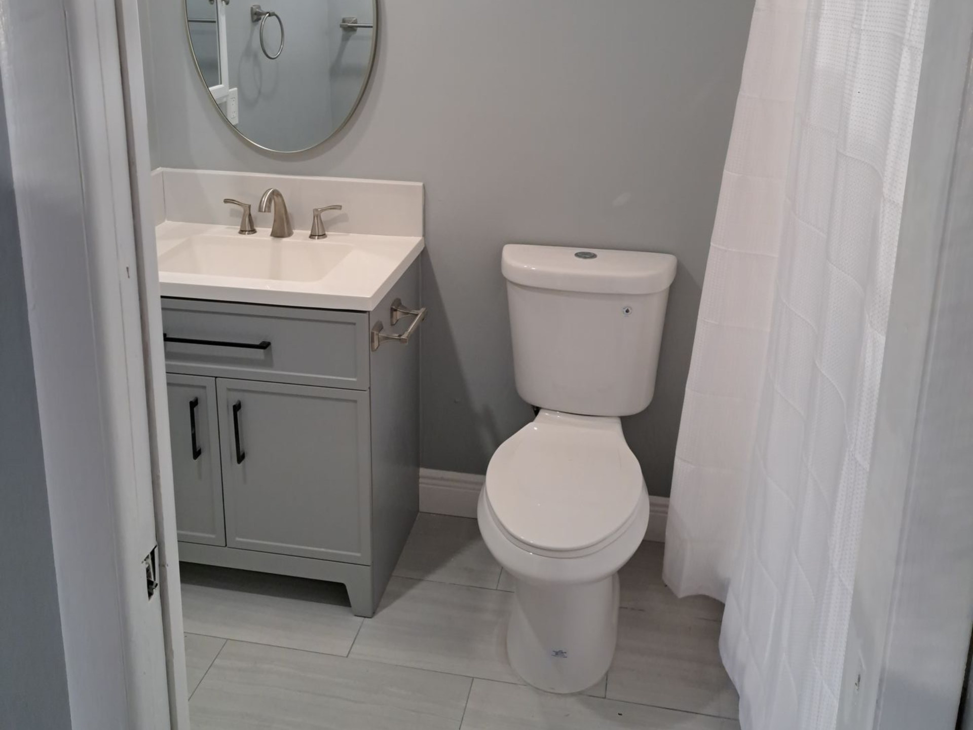 White bathroom with sink, mirror, bathtub, and toilet.
