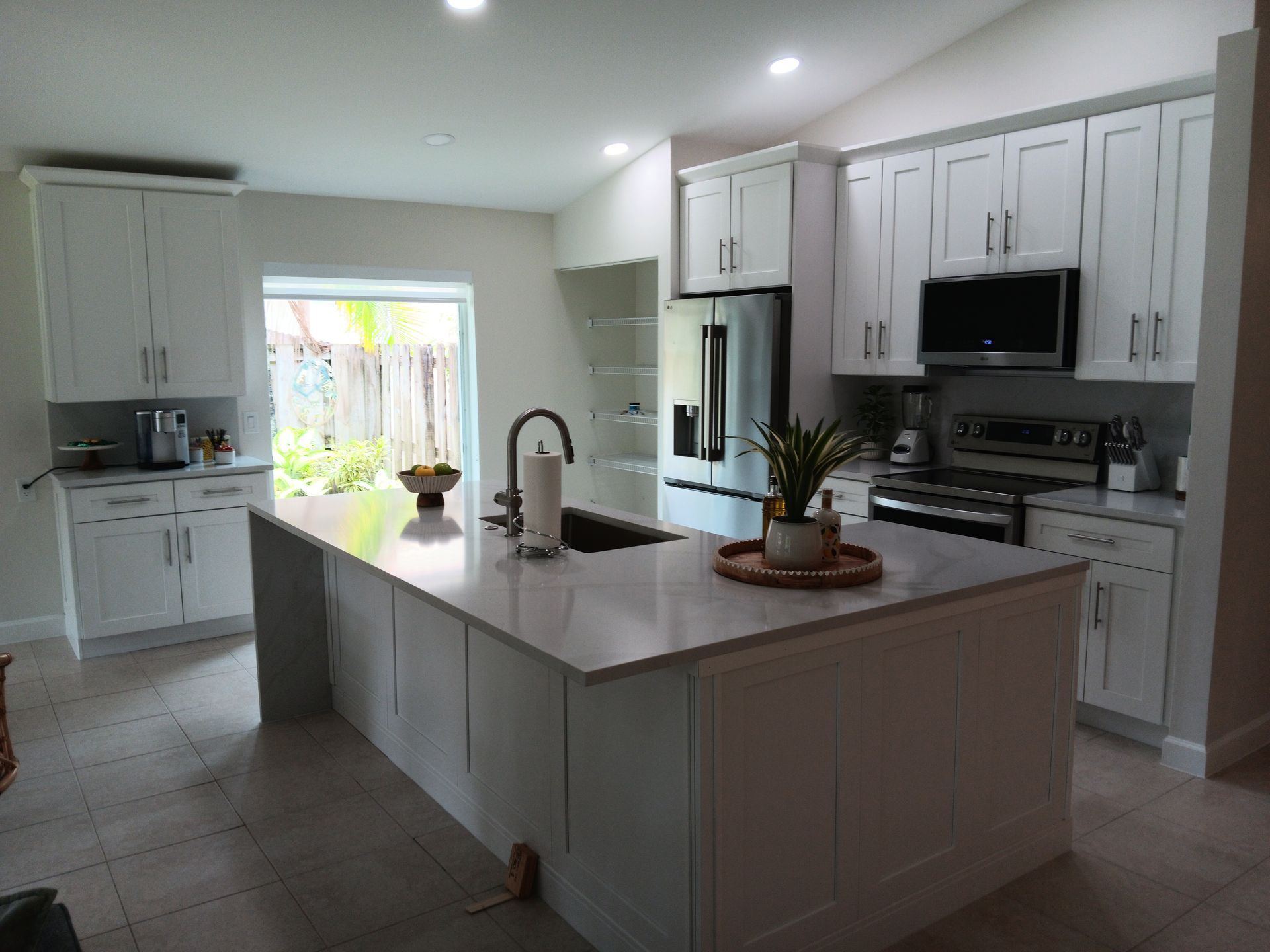 Kitchen renovation in progress: white cabinets installed, countertops and appliances missing, wood floors.