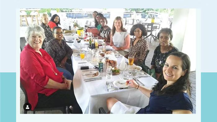 a group of women are sitting at a long table .