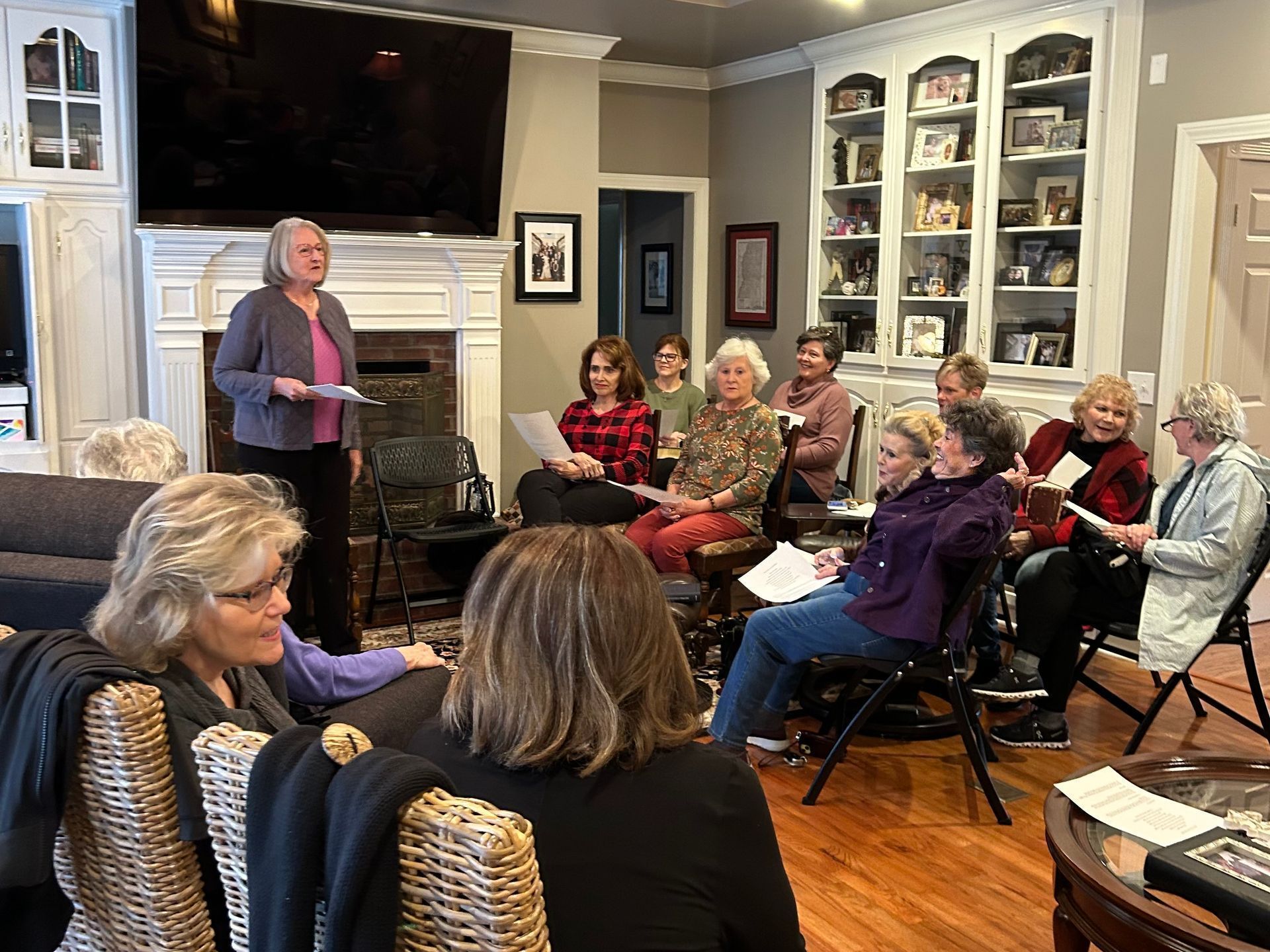 A group of women are sitting around a table in a living room.