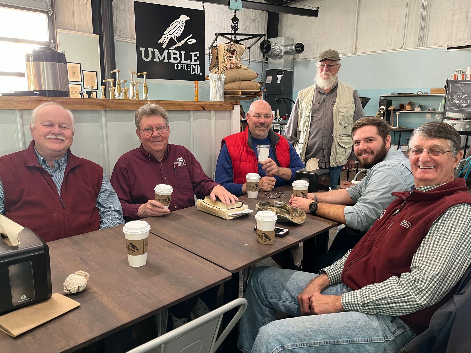 A group of men are sitting around a table with coffee cups.
