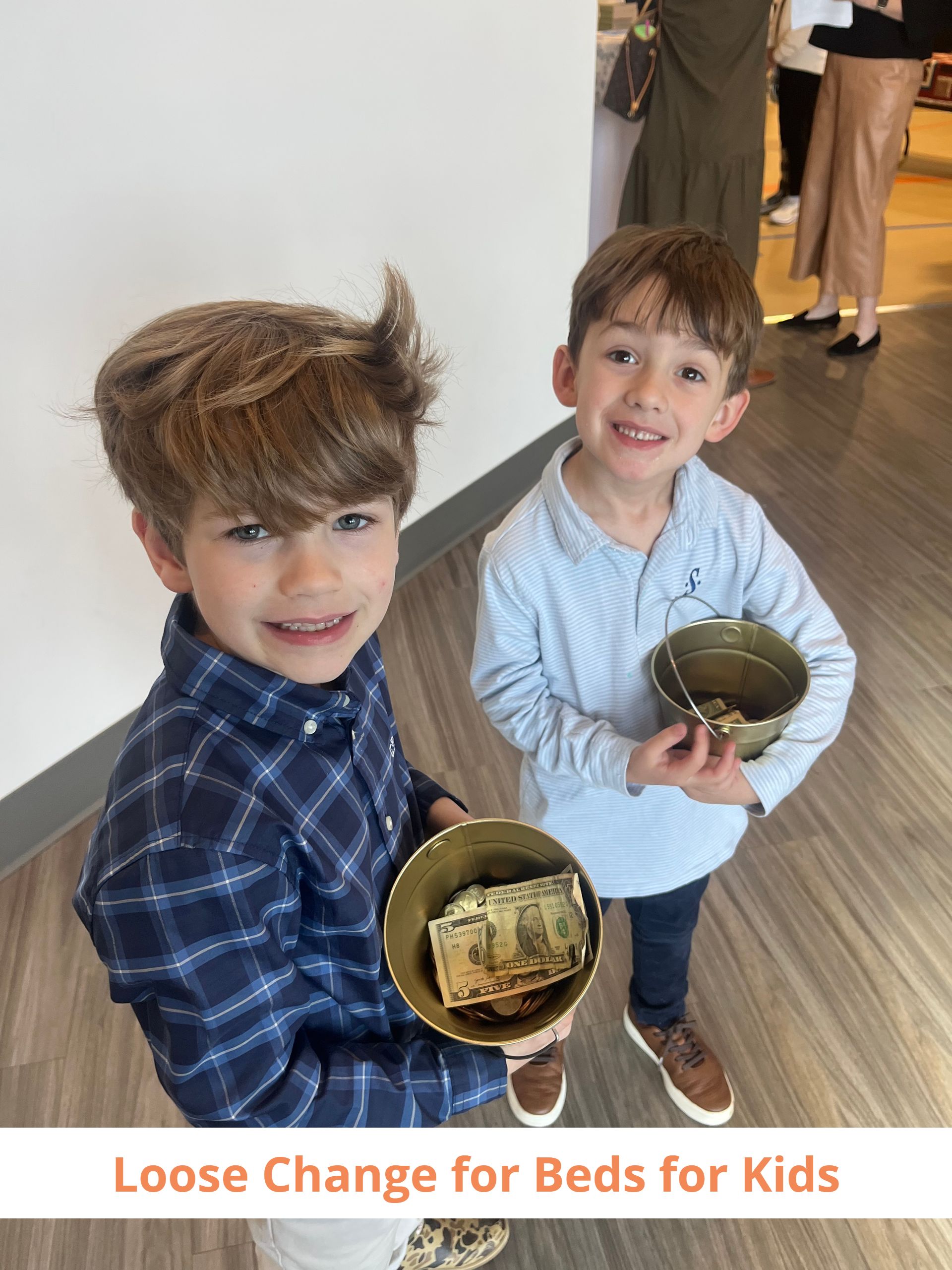 Two young boys are holding bowls of money.