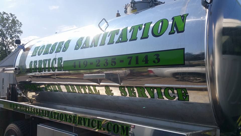 A shiny, chrome-plated sanitation truck with green lettering advertising Horses Sanitation Service and phone number.