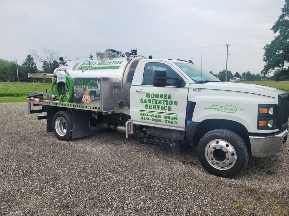 A white Horses Sanitation Service truck with a large tank parked on a gravel lot under a cloudy sky.