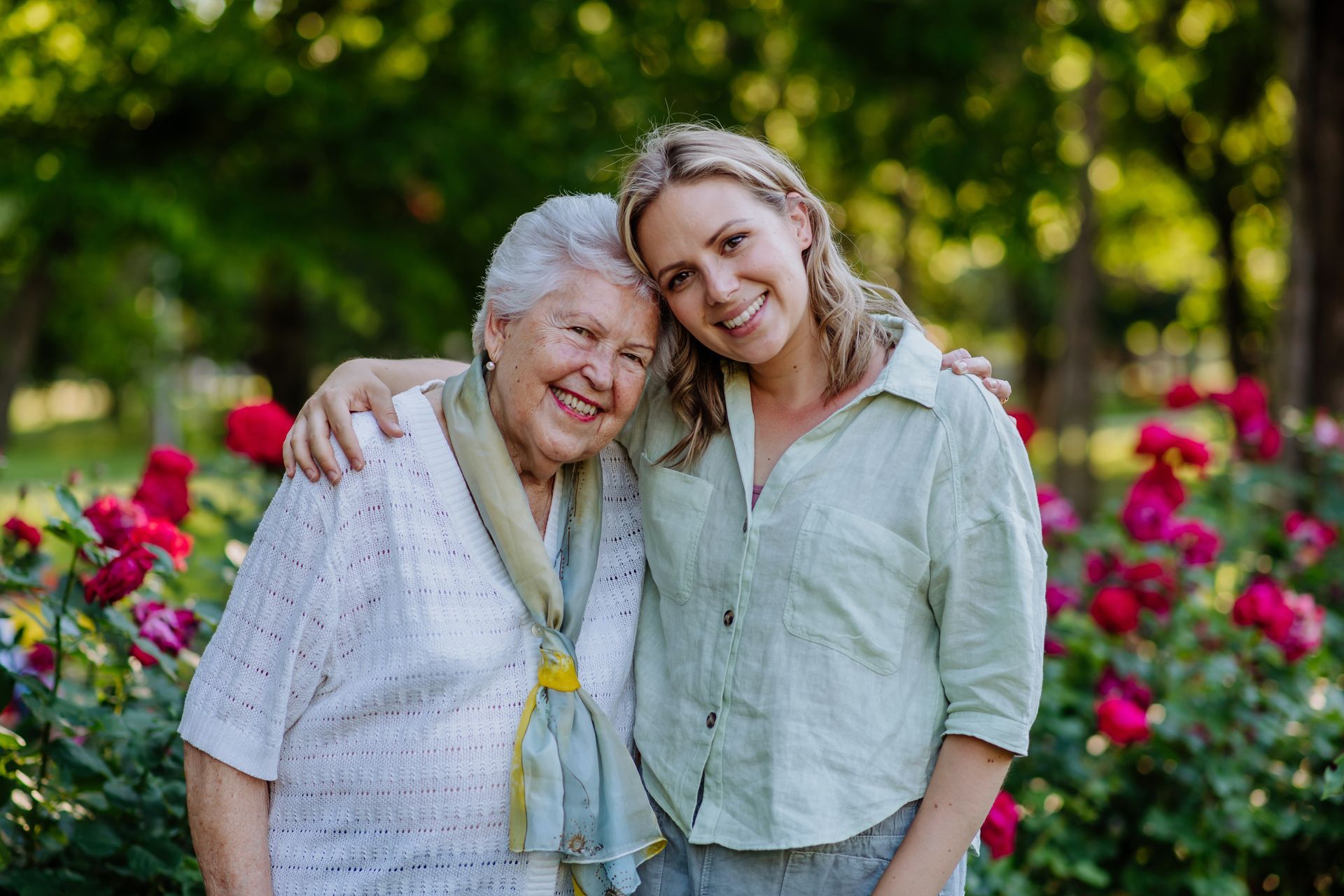 A young woman is hugging an older woman in a park.