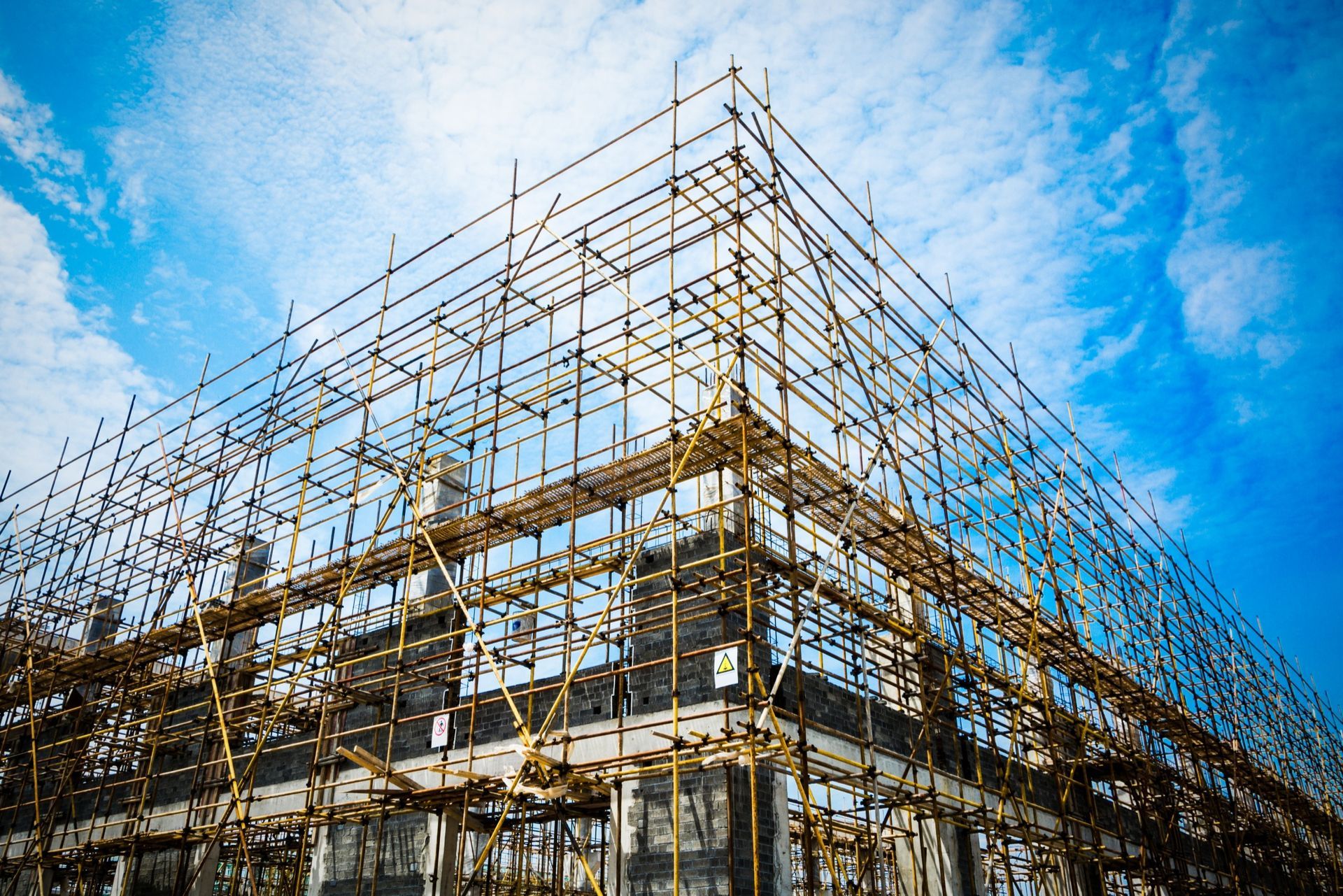 Building under construction with scaffolding against a blue sky.