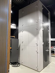 Large, gray, rectangular equipment enclosure in a modern setting, featuring multiple latches and a dark gray section.