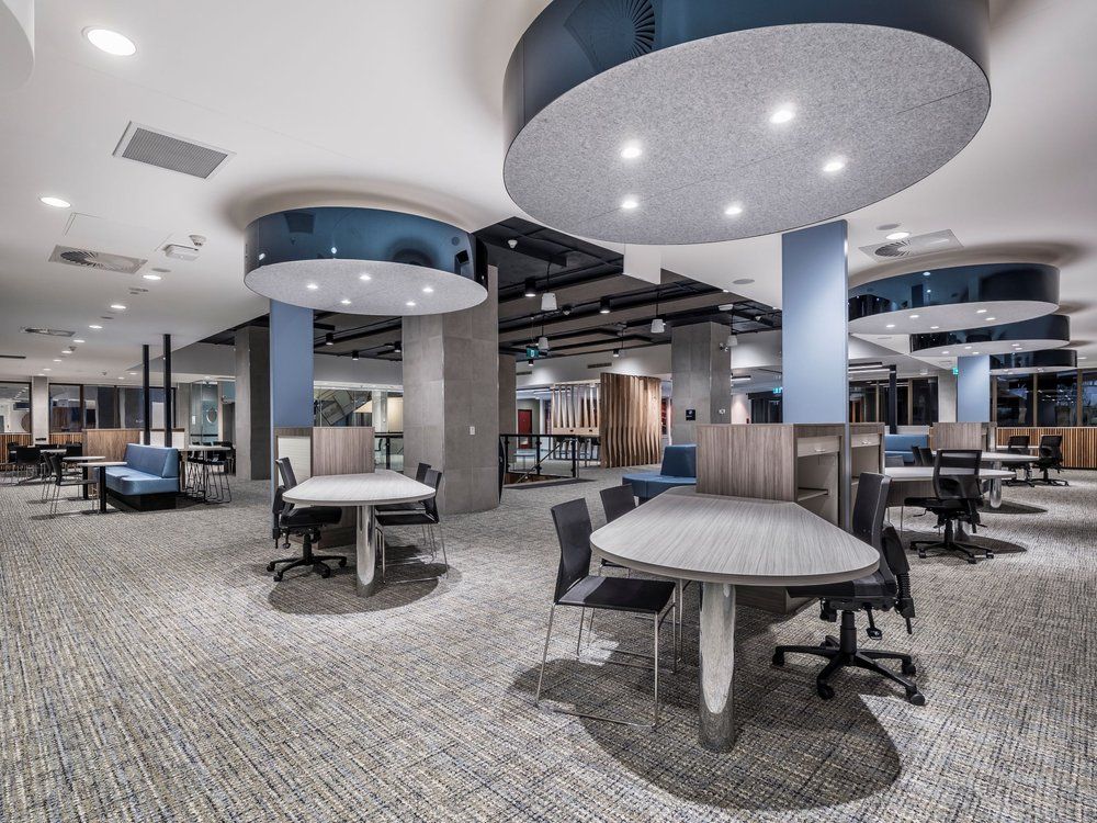 Modern office interior with desks, chairs, and carpet; blue and gray accents, recessed lighting.