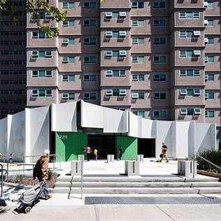 Exterior shot of a modern building with a green entrance and a person pulling a cart.