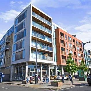 Modern apartment building with glass balconies and retail on the ground floor.