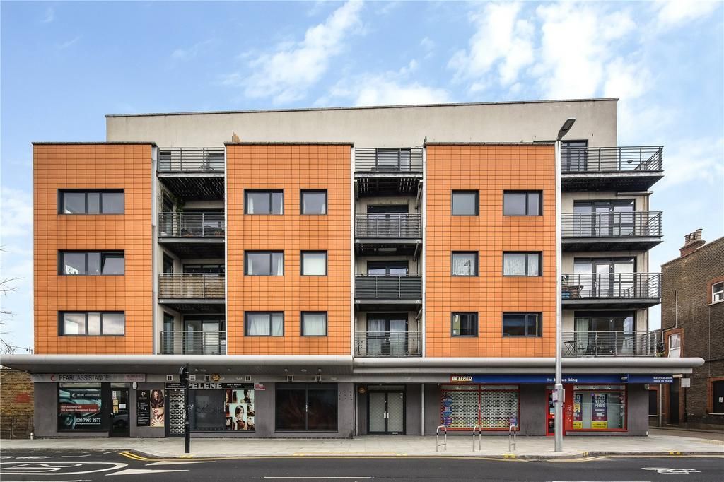 Apartment building with orange panels above storefronts; London street scene.