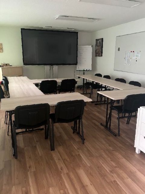 Ein Klassenzimmer mit Tischen und Stühlen und einer großen Leinwand