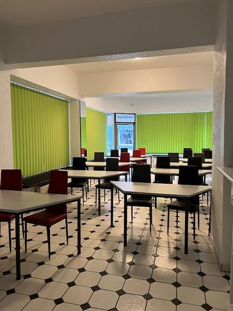 Tische und Stühle in einem Raum mit grünen Jalousien