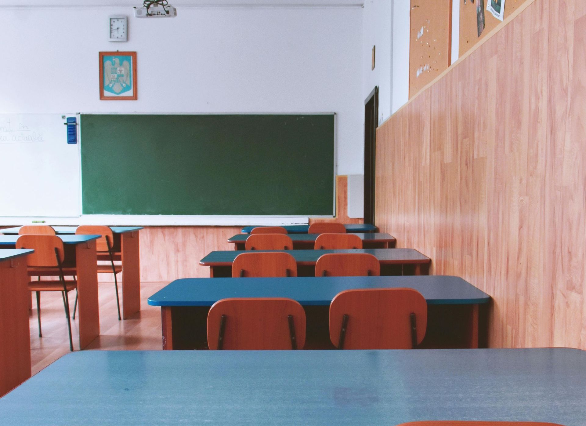 Ein leeres Klassenzimmer mit Tischen und Stühlen und einer grünen Tafel