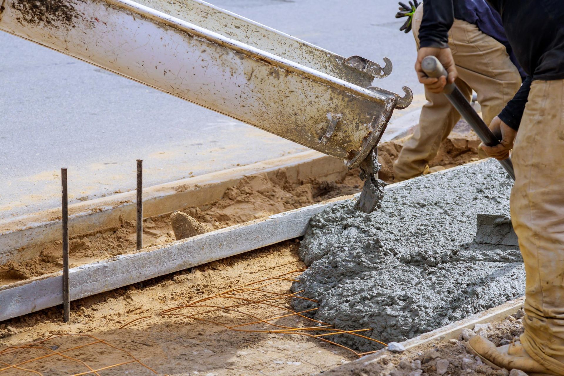Concrete being poured from a truck into a form for a curb. Worker guides the flow.
