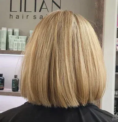 Die Rückseite einer Frau mit blondem Haar ist vor einem Schild eines Lilian-Friseursalons zu sehen.