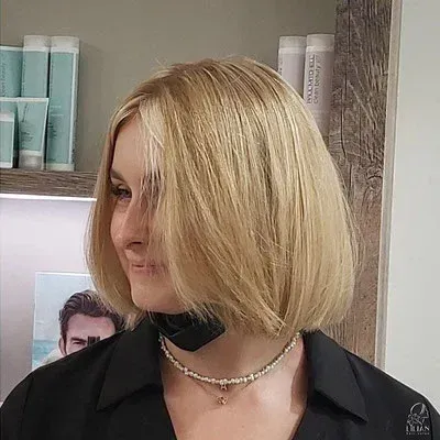 Eine Frau mit blonden Haaren trägt ein schwarzes Hemd und eine Halskette.