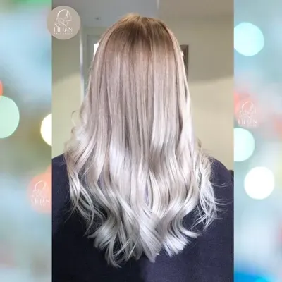 Eine Frau mit langen blonden Haaren steht vor einem unscharfen Hintergrund.