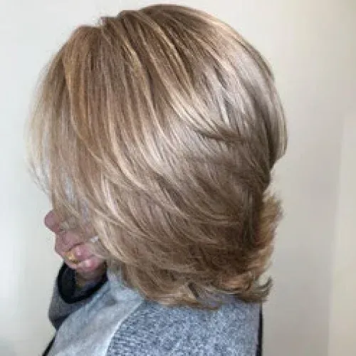 Eine Frau mit langen blonden Haaren trägt einen grauen Pullover.