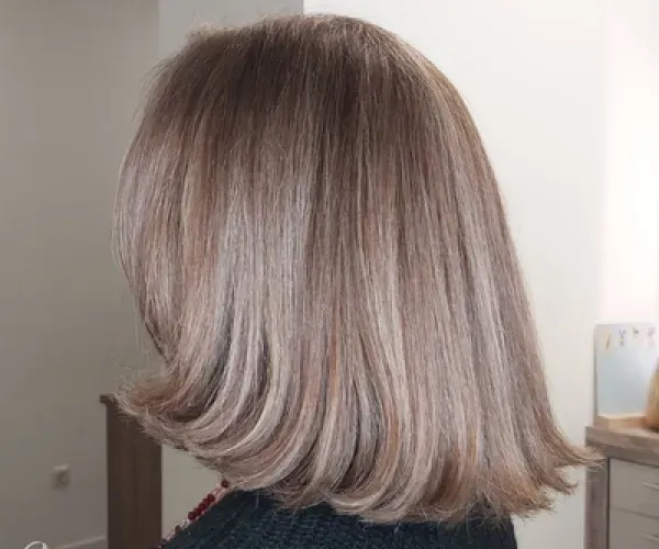 Eine Frau mit langen blonden Haaren trägt einen schwarzen Pullover.