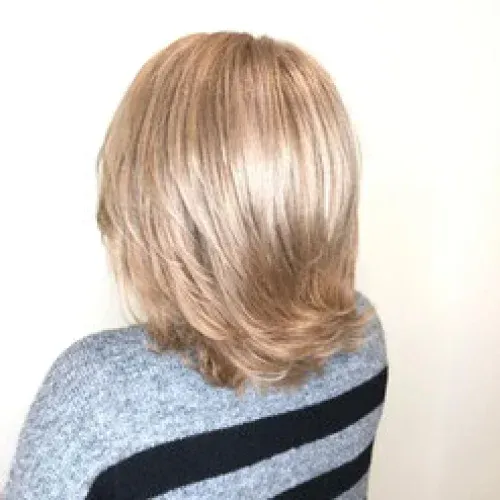 Eine Frau mit blonden Haaren trägt einen blau-schwarz gestreiften Pullover.