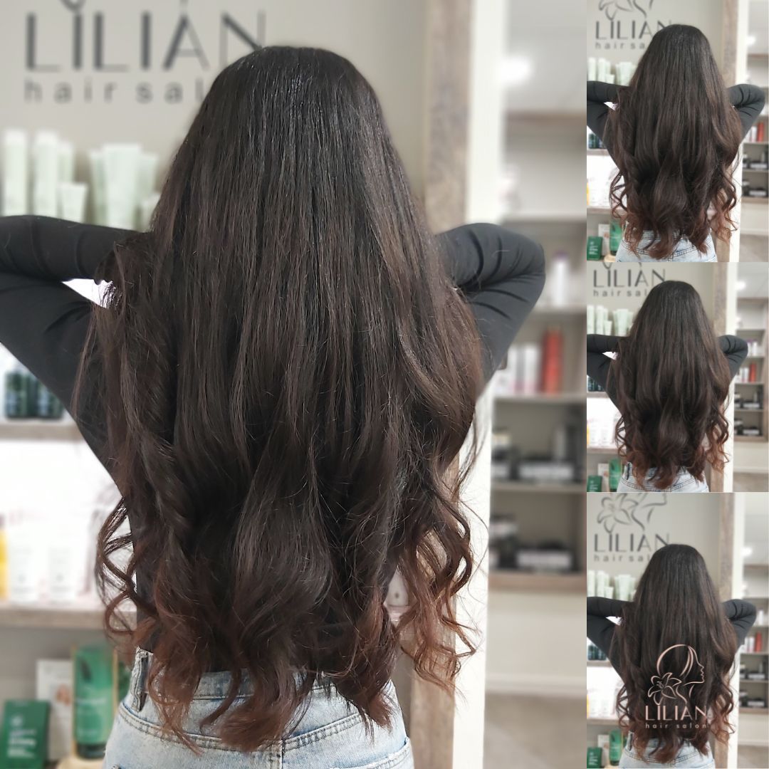 Eine Frau mit langen Haaren steht in einem Friseursalon vor einem Spiegel.