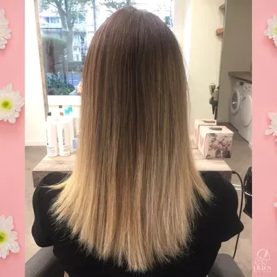 Eine Frau mit langen blonden Haaren sitzt in einem Stuhl in einem Salon.
