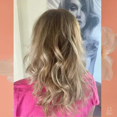 Eine Frau mit langen blonden Haaren trägt ein rosa Hemd.
