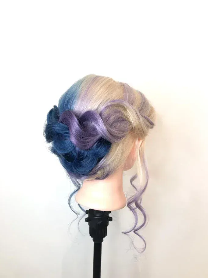 Eine Schaufensterpuppe trägt einen Dutt und hat blaue und violette Haare.
