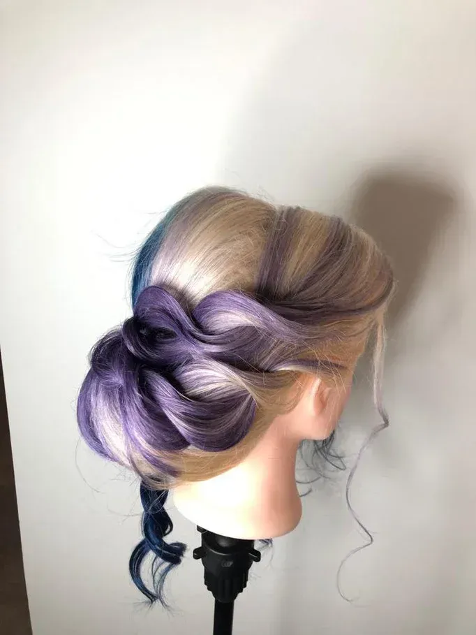 Ein Schaufensterpuppenkopf mit blondem und violettem Haar zu einem Dutt gebunden.