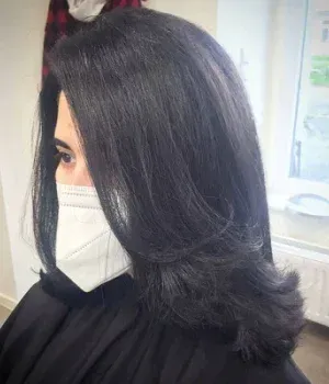 Eine Frau mit langen schwarzen Haaren trägt eine Gesichtsmaske.