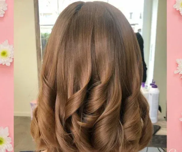 Eine Frau mit langen braunen Haaren steht vor einem Spiegel.