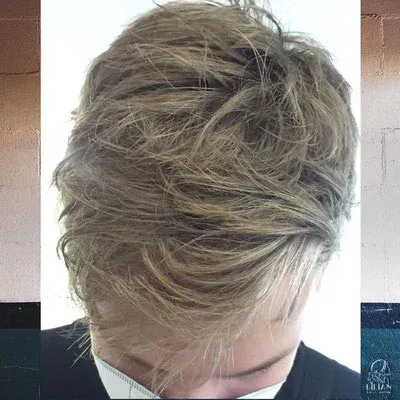 Ein Mann mit blondem Haar bedeckt sein Gesicht mit seiner Hand.