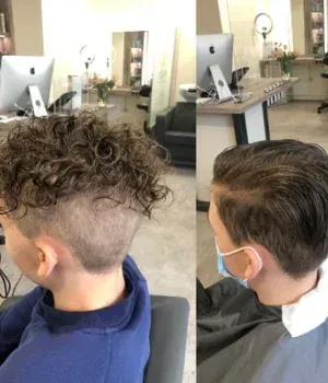 Ein Mann mit lockigem Haar lässt sich in einem Salon die Haare schneiden.