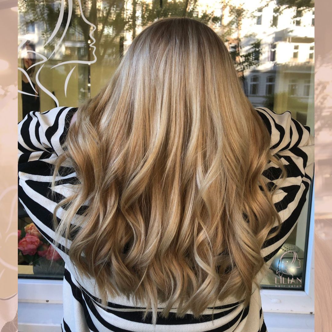 Eine Frau mit langen blonden Haaren steht vor einem Fenster.