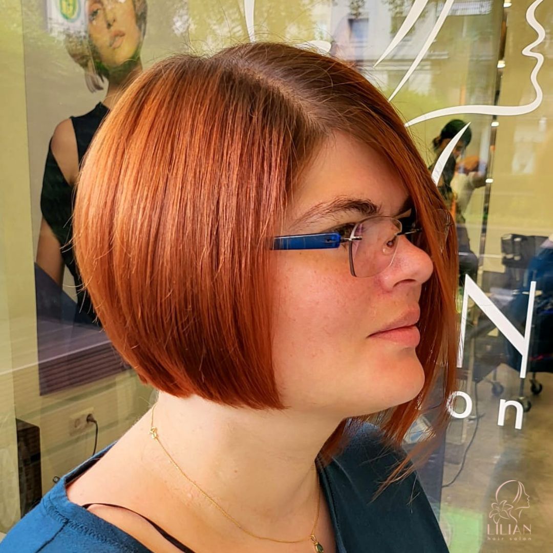 Eine Frau mit roten Haaren, einer Brille und einem blauen Hemd