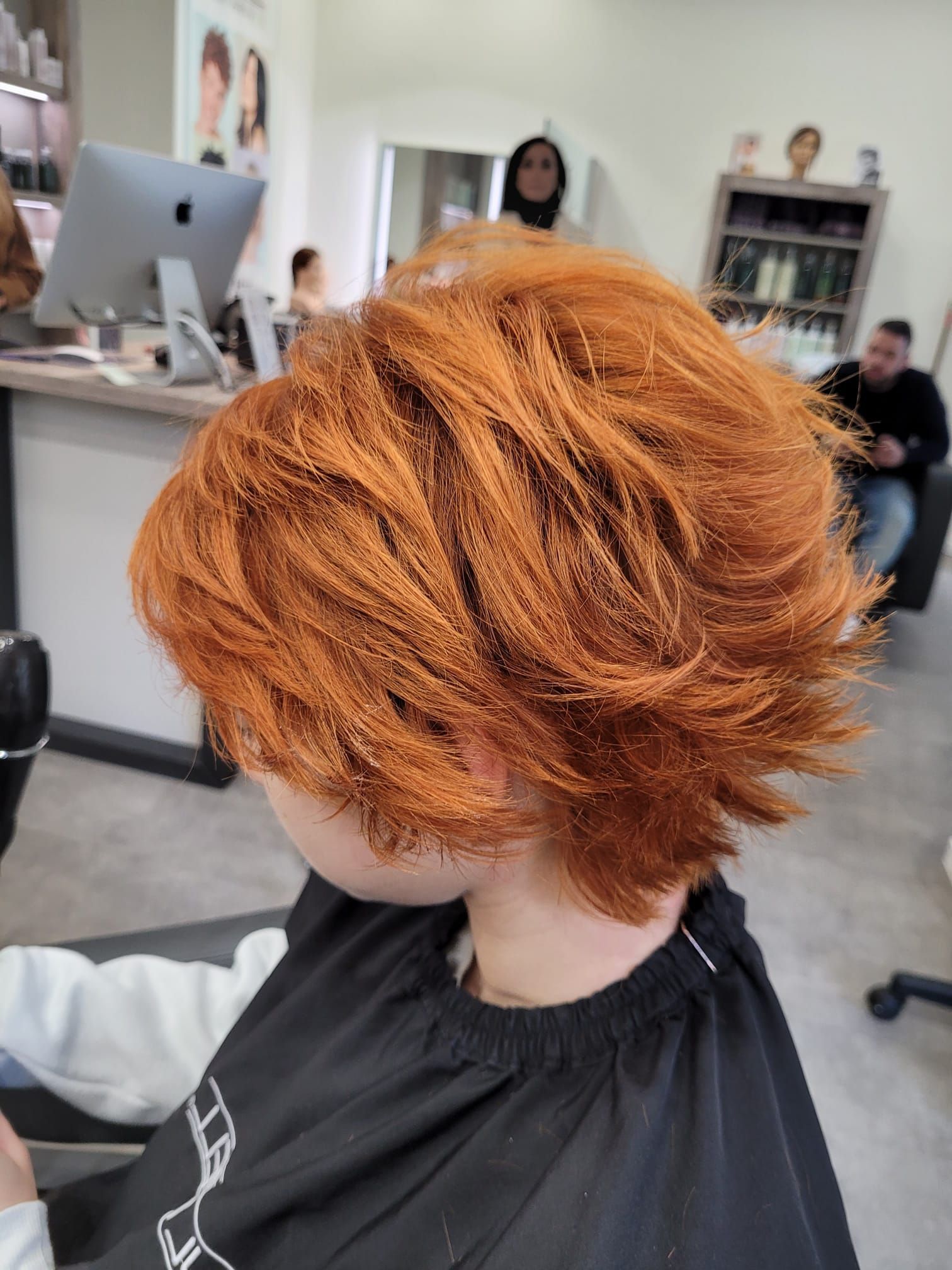 Eine Frau mit roten Haaren lässt sich in einem Salon die Haare schneiden.