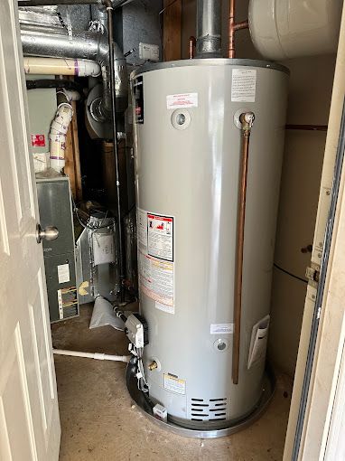 A water heater is sitting in a room next to a furnace.