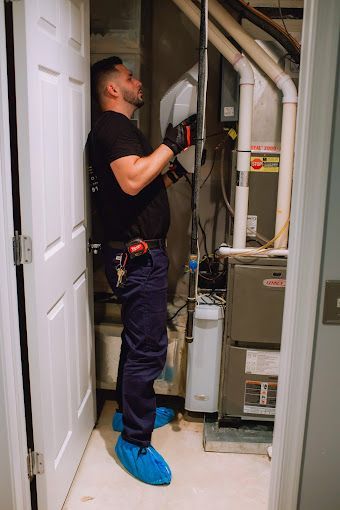 A man is working on an air conditioner in a basement.