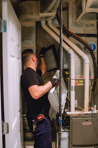 A man is working on an air conditioner in a basement.