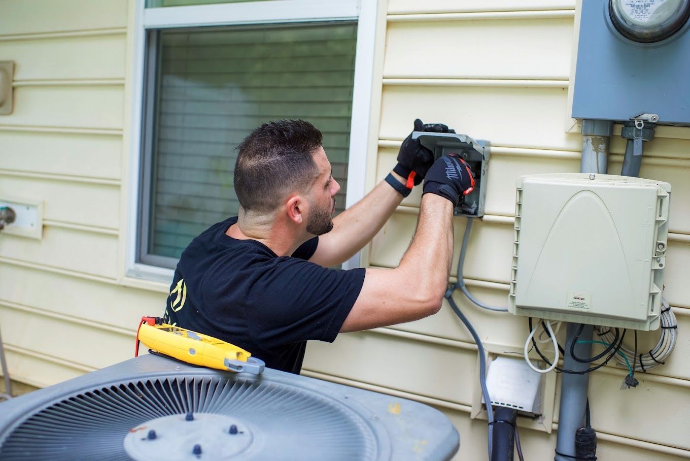 a man is working on an air conditioner outside of a house .