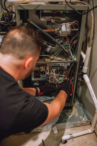 A man is working on an air conditioner in a basement.