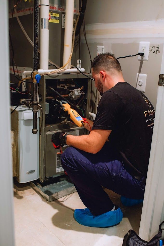 a man is kneeling down in front of a furnace while working on it .