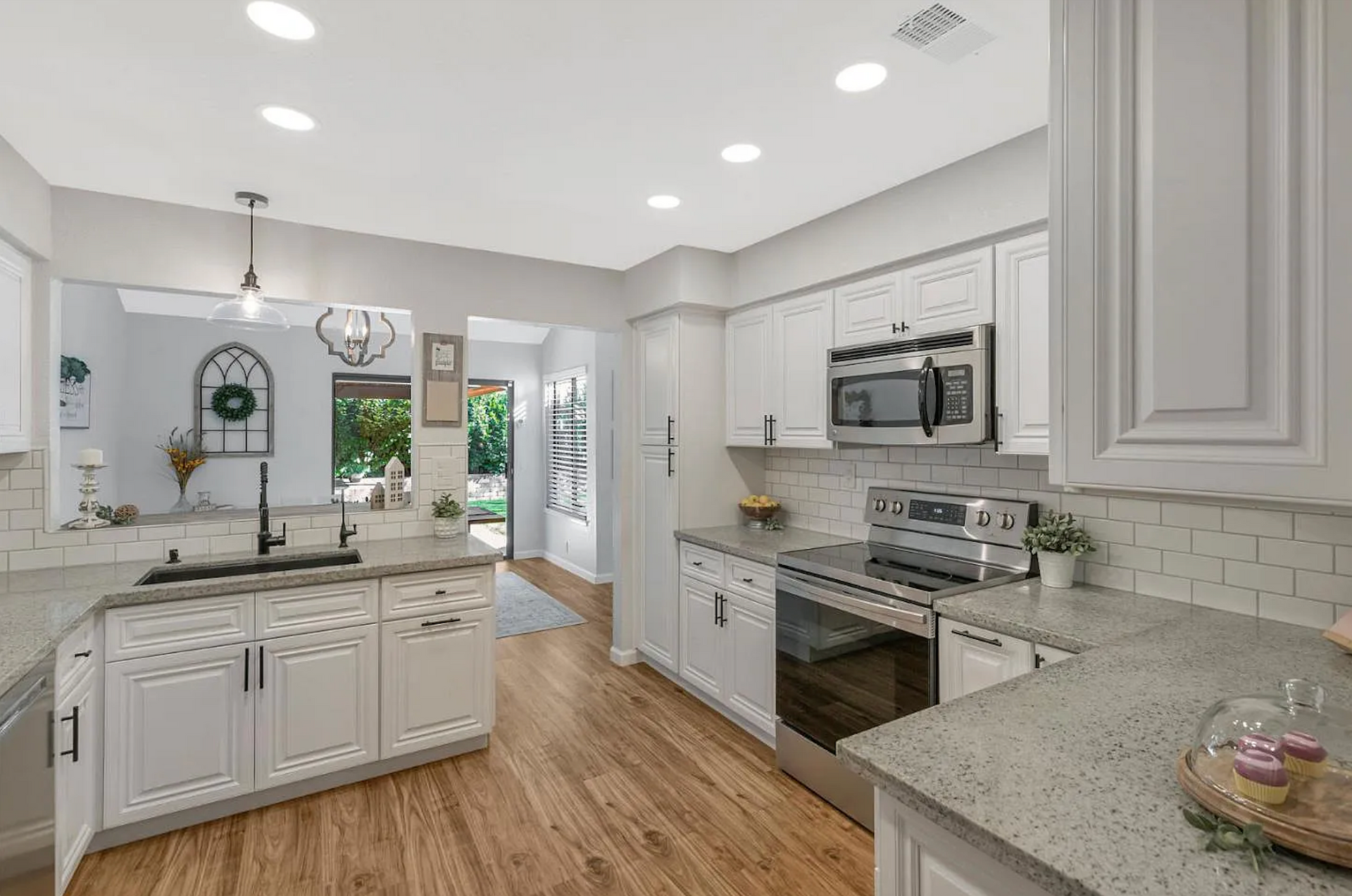 Bright kitchen with white cabinets, stainless steel appliances, and wood floors.