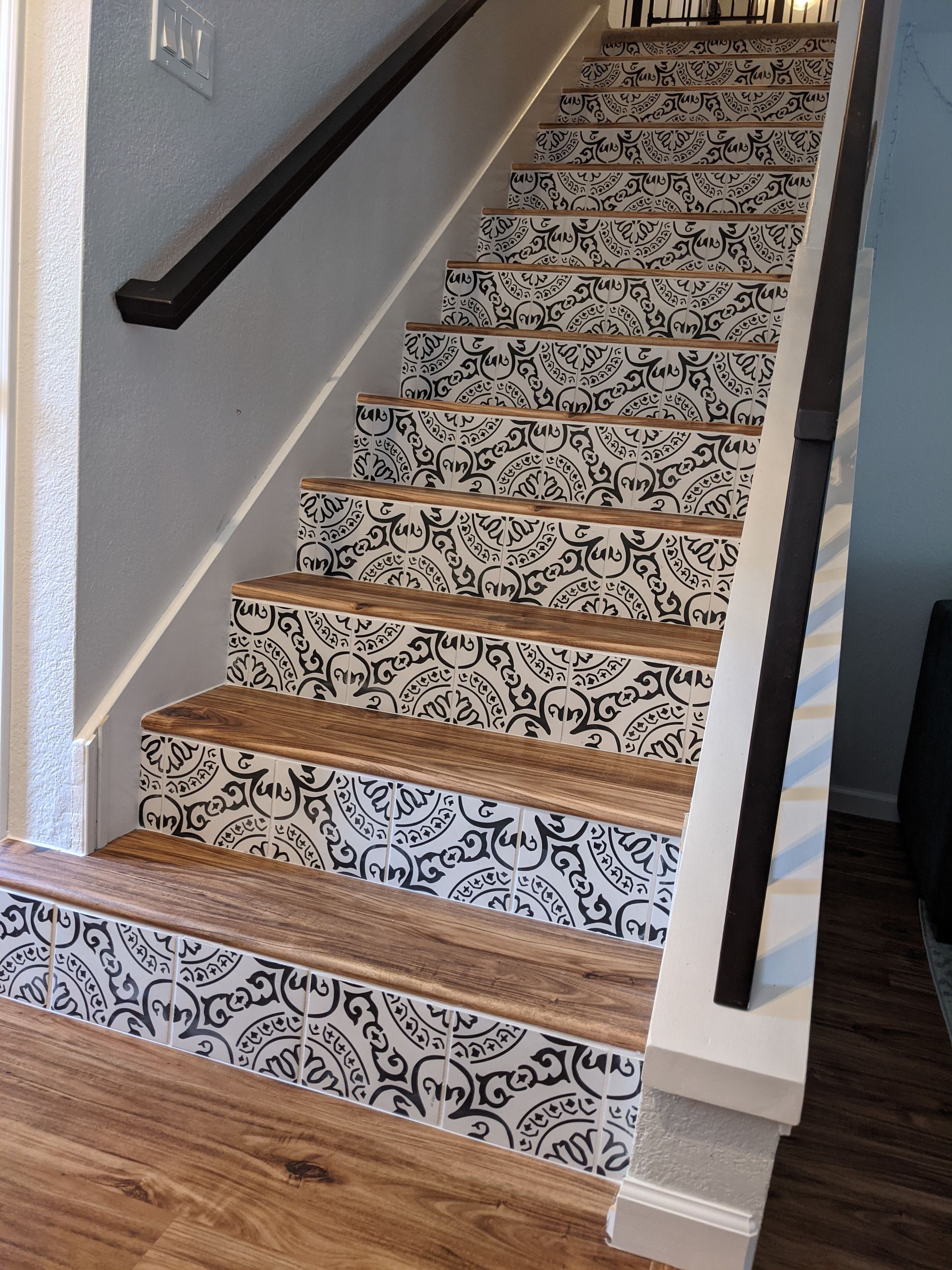 Staircase with patterned risers. Wooden steps and railings. White walls.