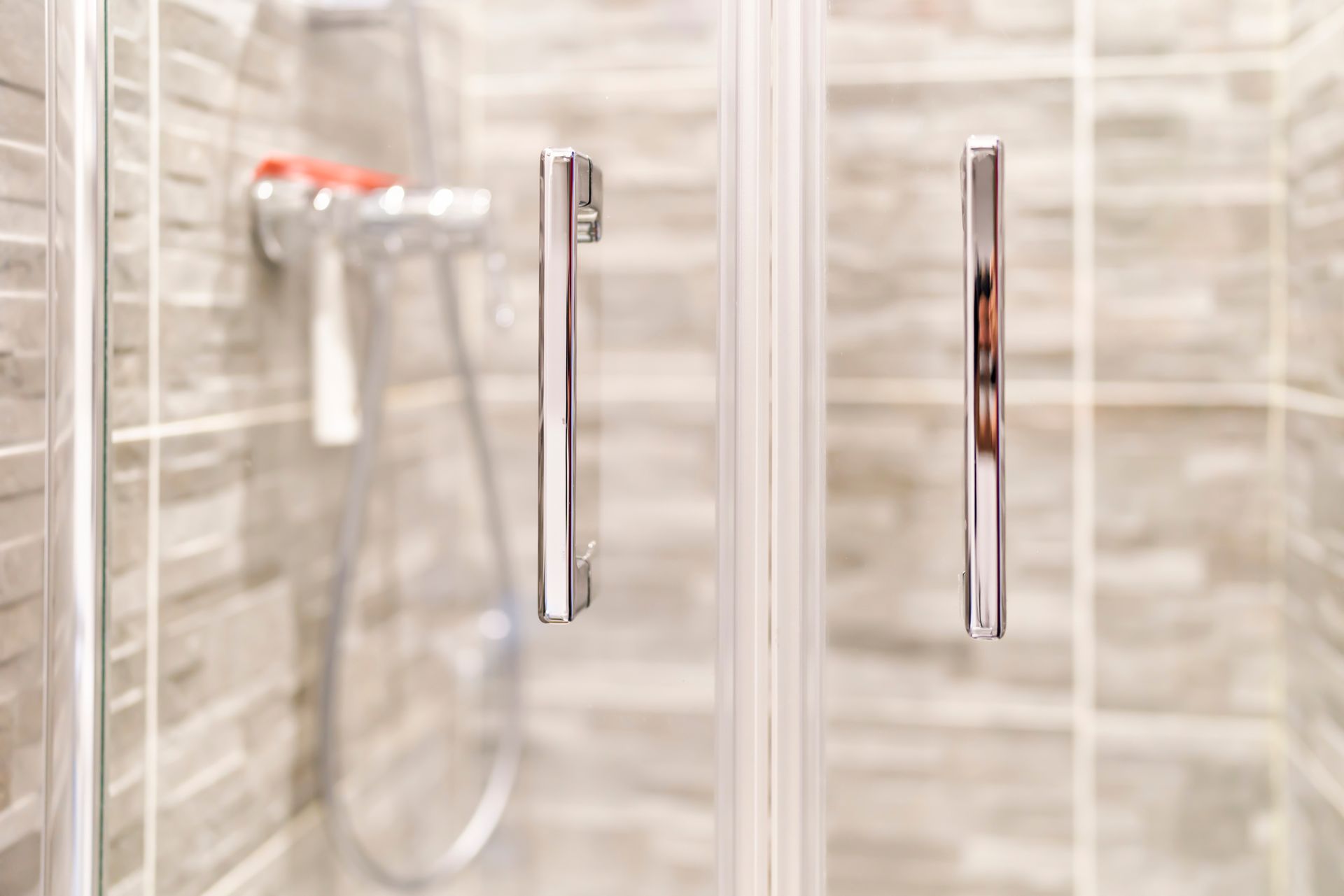 Close-up of shower door handles in modern bathroom.