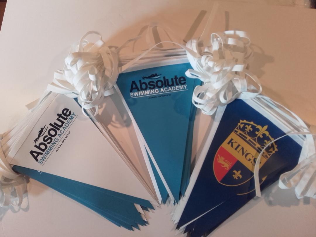 Three absolute swimming academy flags are on a table