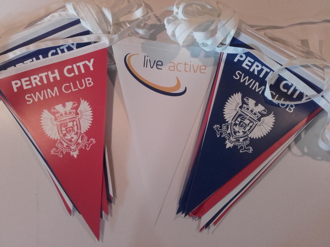 Three perth city swim club flags on a table